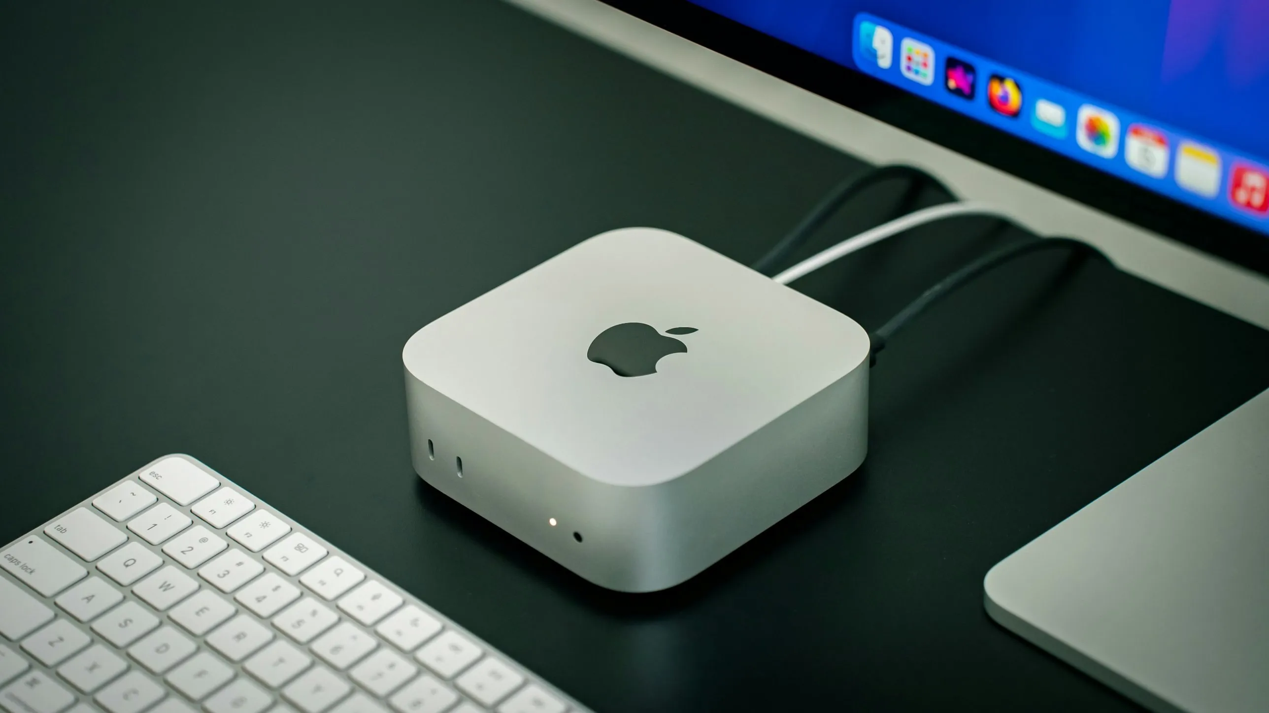 Mac mini posé sur un bureau, à côté d'un clavier et d'un écran